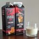 Two cartons of Fireball Non-Alcoholic Cinnamon Holiday Nog beside a glass full of nog